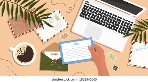 Envelopes, letters, postcards and a laptop on the table. Envelope in hand. Workspace and table top view. Woman sends a postcard in flat hand drawn style. Vector stock illustration.