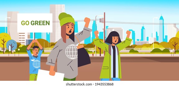environmental activists holding posters go green save planet strike concept protesters campaigning to protect earth demonstrating against global warming portrait cityscape background horizontal