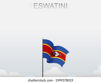 The Eswatini flag flying on a pole standing tall under a white sky