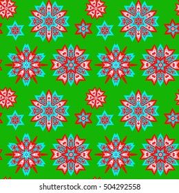 Ethnic Christmas seamless pattern on green background. Boho textile print. New Year wallpaper. Winter red wrapping with snowflakes.