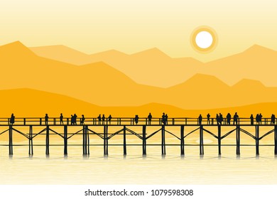 Evening atmosphere A wooden bridge with people walking there is a mountain backdrop. The wooden bridge is silhouette.