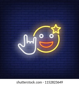 Excited emoticon with cool gesture neon sign. Star on smiley, showing rock symbol. Night bright advertisement. Vector illustration in neon style for rock concert and spectacular