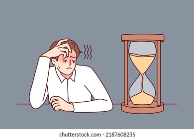 Un empresario exhausto que mira el reloj de arena se siente aburrido y abrumado. Empleado masculino cansado mira el reloj de arena esperando el final del día laboral. Ilustración vectorial. 