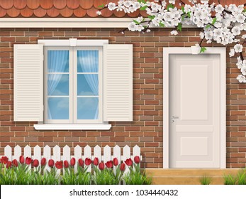 The facade of a country house in the spring. Brick wall with window and door. In the front garden grow red tulips.