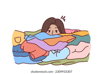Face of woman near dirty clothes in need of washing with colored laundry detergent. Girl housewife or maid drowns in dirty linen due to overwork and overload with household chores.