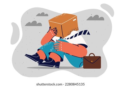 Fallen man with cardboard box on head for concept of disorientation and lack of strategy for company. Man in business clothes sits on ground hiding face behind box and delivery service 