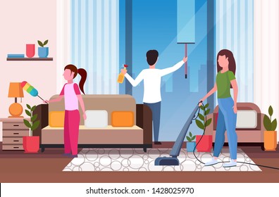family doing housework together father wiping glass window mother using vacuum cleaner daughter dusting cleaning housekeeping concept modern living room interior full length horizontal