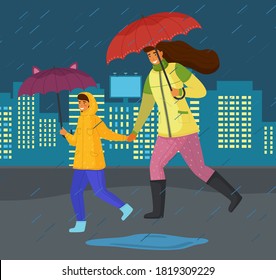 Family mother and son hurry at urban street during rain, adult woman and boy teenager with umbrellas, people wearing boots, running at puddles, night time buildings with light in windows at background