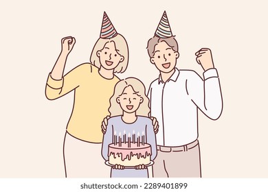 Family of parents with daughter celebrating birthday posing with cake and candles for joint photo. Mother and father together with pre-teenage girl celebrating birthday party making joyful gestures 