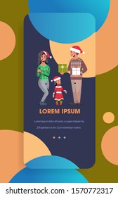 family in santa hats holding gift present boxes parents and daughter celebrating merry christmas happy new year winter holidays concept smartphone screen online mobile app full length vertical vector