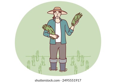 Farmer girl on rice plantation with rice sprouts during harvest season of organic wheat crop. Farmer woman in hat stands in water on plantation for growing organic products for sale at farmers fair