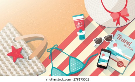 Fashion beach accessories on the sand, towel, swimming costume, bag, mobile phone, magazine and sun lotion, travel and holidays concept with copy space