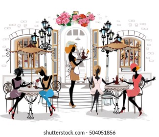 Fashion girls in the street cafe. Street cafe with flowers in the old city. Waiters serve the tables.