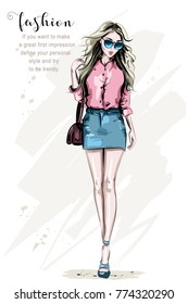 Fashion model posing. Hand drawn stylish woman in fashion clothes. Beautiful young woman with bag. Cute girl in sunglasses. Sketch.