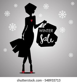 Fashion shopping woman black silhouette in red high heels with shopping bags with sign on it Winter Sale advertising with snowflakes background template - vector illustration