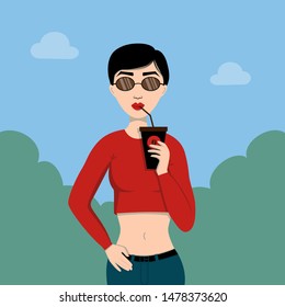 Fashionable girl with glasses standing in the Park and drinking coffee from a tube. Can be used for advertising, articles and posts.