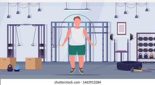 fat obese man doing exercises with jumping rope overweight guy training workout weight loss concept modern gym health club studio interior flat full length horizontal