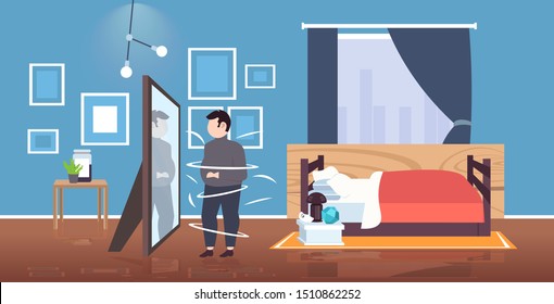 fat overweight man looking at reflection in mirror sad obese guy unhealthy lifestyle obesity concept modern bedroom interior horizontal flat full length