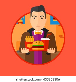 A fat young man holding tray full of junk food. Smiling man in fast food restaurant. Man having lunch in a fast food restaurant. Vector flat design illustration in the circle isolated on background.
