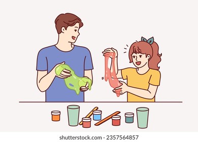 Father and daughter conduct chemical experiments holding and playing with slime, developing intelligence and creativity of child. Happy teenage boy showing little sister funny reaction chemicals