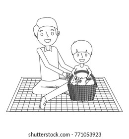 father with her son sitting on blanket with food basket