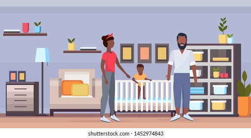 father mother and newborn baby in crib having fun together happy african american family parenthood concept modern baby's bedroom interior full length horizontal flat