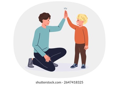 Father supports young son by high-fiving boy and raising child on own after divorce from mother. Young single dad smiles while communicating with son, celebrating father family day