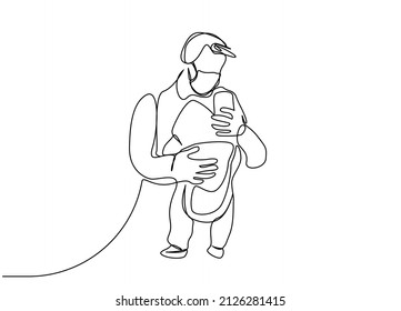 The father, who wears a mask to protect himself from the virus, carries his baby hanging in front of him and takes pictures while walking outside.ergonomic baby carrier
