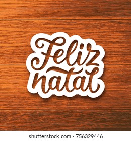 Feliz Natal portuguese Merry Christmas text on white paper cut style label over wood background. Lettering for season greetings. Vector background