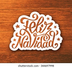 Feliz Navidad text lettering with stars on white paper label and wooden vector background. Typography for Merry Christmas greeting card, invitation or poster design in spanish