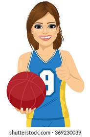 female basketball player holding ball and showing thumbs up