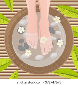 Female feet at spa pedicure procedure. Legs, flowers and ceramic bowl.