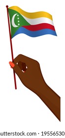 Female hand gently holds small flag of Comoros islands. Holiday design element. Cartoon vector on white background