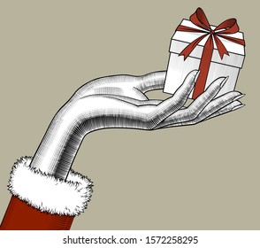 Female hand holding a small gift box with red ribbon and bow. Vintage engraving stylized drawing. Vector illustration