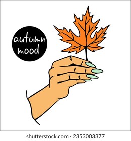Female hand holds an autumn maple leaf. Autumn mood. In his hand, a yellowed autumn leaf.