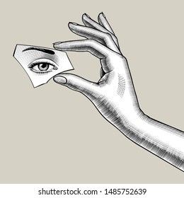 Female hand holds a mirror splinter in the fingers with eye reflection. Vintage engraving stylized drawing. Vector Illustration