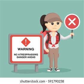 female hiker standing beside danger sign