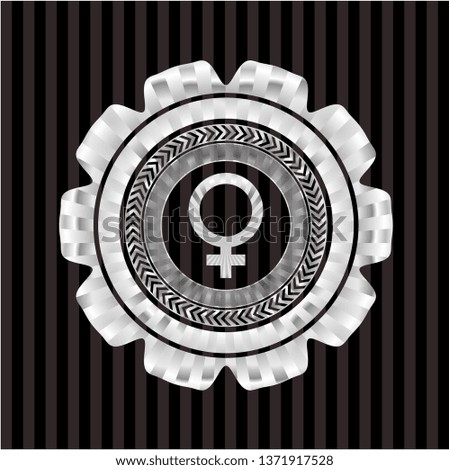 female icon inside silvery emblem