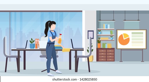 female janitor in uniform wiping conference table by dust cloth cleaning service concept full length flat modern office interior horizontal