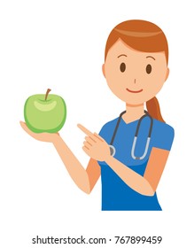 A female nurse wearing a blue scrub has a green apple