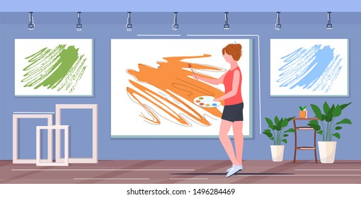 female painter using paintbrush and palette woman artist standing and painting picture on wall art creativity hobby creative occupation concept modern studio gallery interior full length horizontal