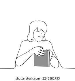 female student opens a book sitting at the table - one line drawing vector. the concept of a reader in the library, book addiction, a student with a textbook