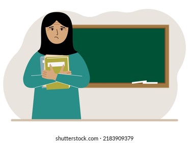 Female teacher with books on the background of the school board.
