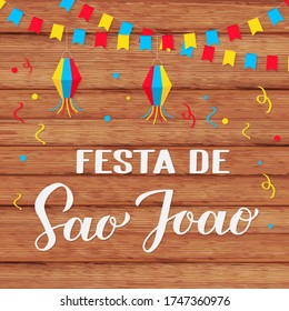 Festa de Sao Joao calligraphy  hand lettering with paper lanterns and flags on wooden background. Brazil June holiday Festa Junina. Vector template for typography poster, banner, invitation, flyer.