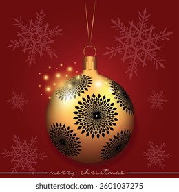 A festive gold Christmas ball with decorative black flowers on a red backdrop.
