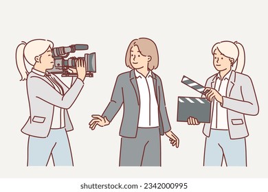 Film crew of cameraman and female assistant with clapboard near TV presenter. Process of film production and shooting new take of hollywood blockbuster or going live for news release