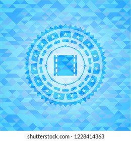 film icon inside sky blue emblem with triangle mosaic background