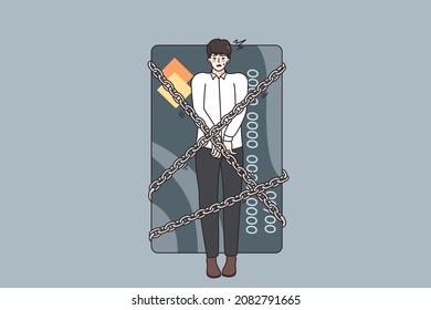 Financial crisis and debts concept. Young stressed man being locked with chains to huge credit card having debts as slave over grey background 