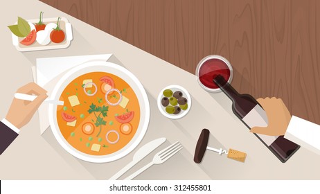 Fine dining at restaurant, a customer is eating a tasty soup and a waiter is pouring wine in a glass