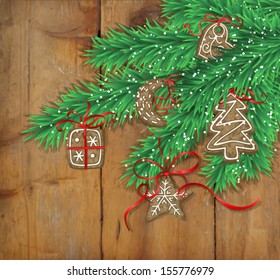 Fir branches covered with snow, decorated with Christmas cookies - tree, star, gift, moon and heart- with bows on wooden background